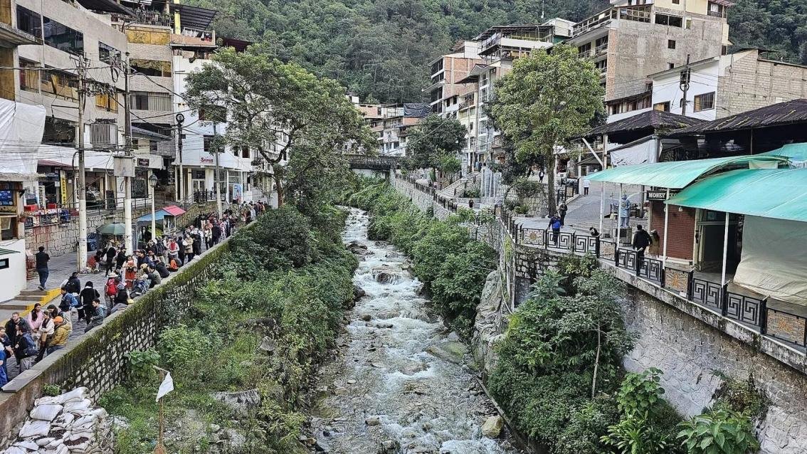 Aguas Calientes town between steep green mountains with the Urubamba River below