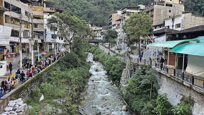 Aguas Calientes town between steep green mountains with the Urubamba River below