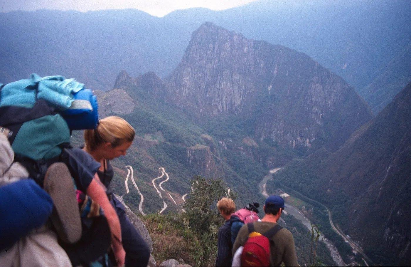 Hikers above Machu Picchu Hikers with backpacks look down at the switchback road below Machu Picchu and the Urubamba valley