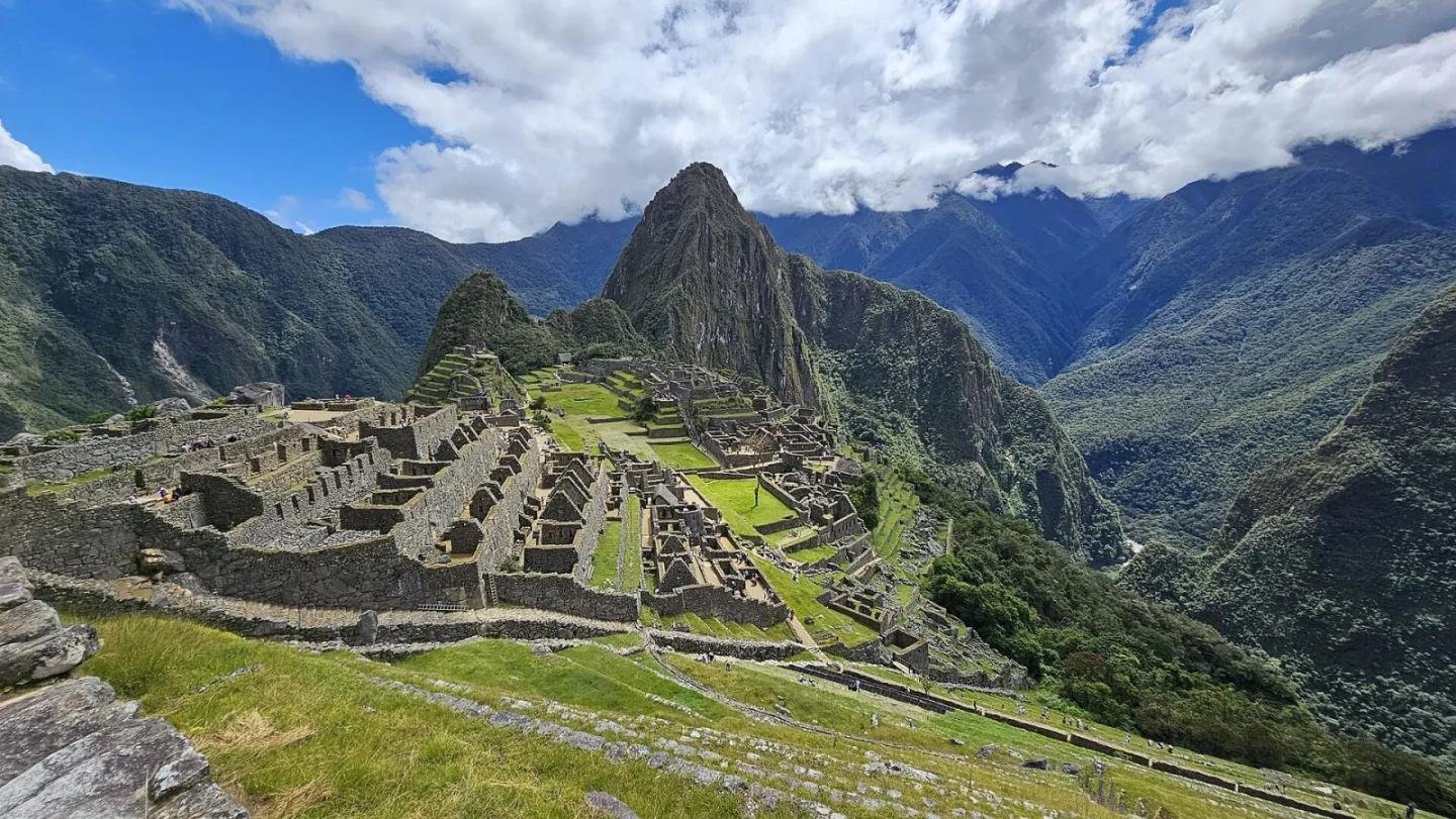 Machu Picchu and Huayna Picchu Machu Picchu with Huayna Picchu behind the ruins under a partly cloudy sky