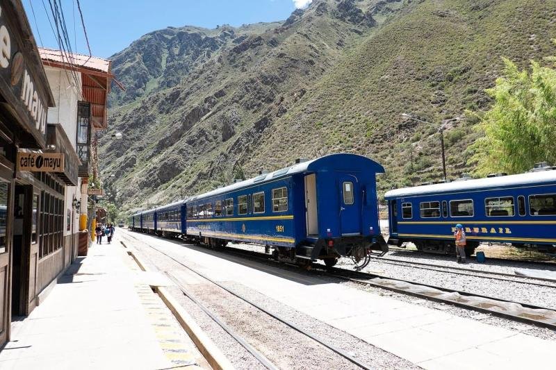 PeruRail at Ollantaytambo station Blue PeruRail carriages waiting at Ollantaytambo station below dry mountain slopes