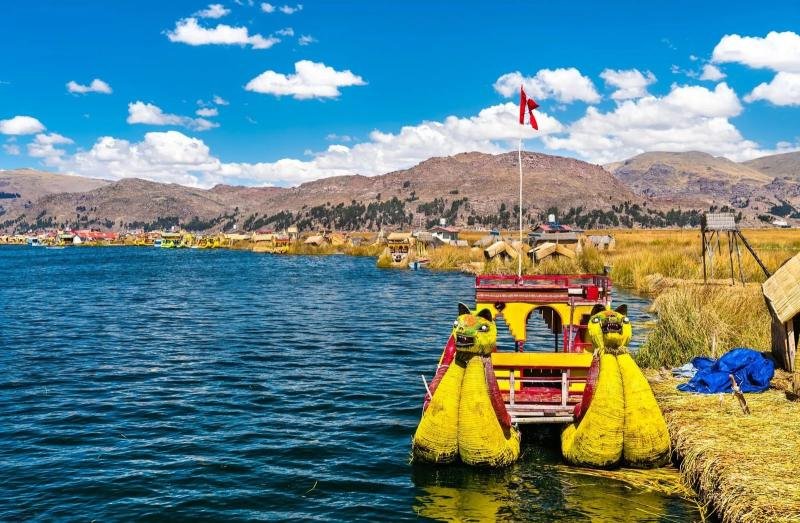 Reed boat at the Uros islands Puma-headed totora reed boat with a Peruvian flag at the Uros islands, Lake Titicaca