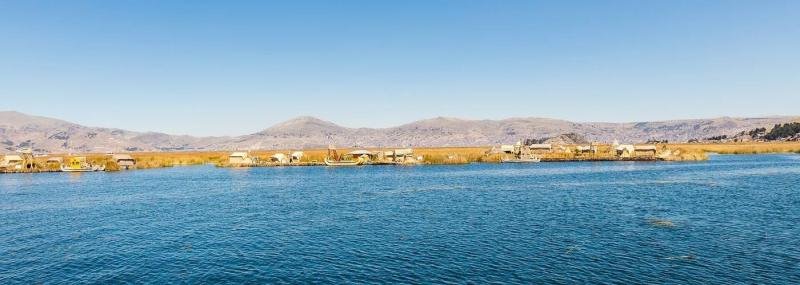 Uros islands, Lake Titicaca Uros floating reed islands seen across the deep blue water of Lake Titicaca
