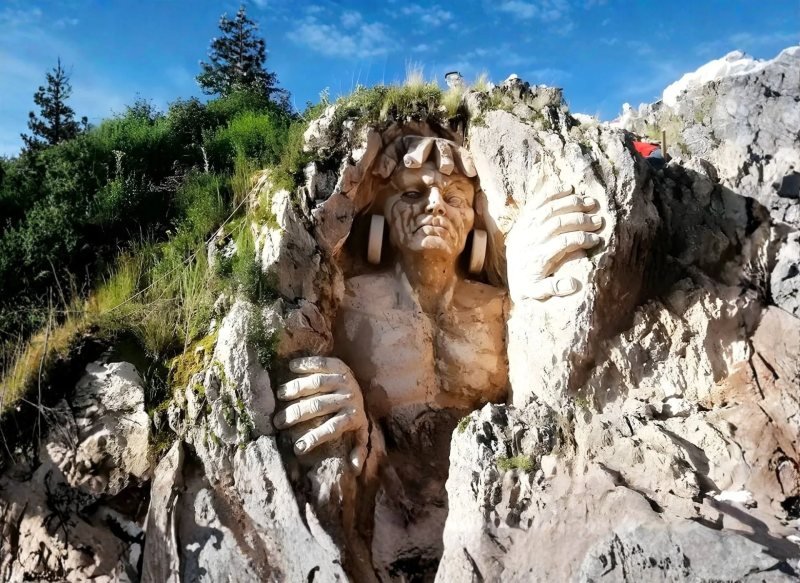 Giant face and hands carved into a white rock outcrop at Apukunaq Tianan