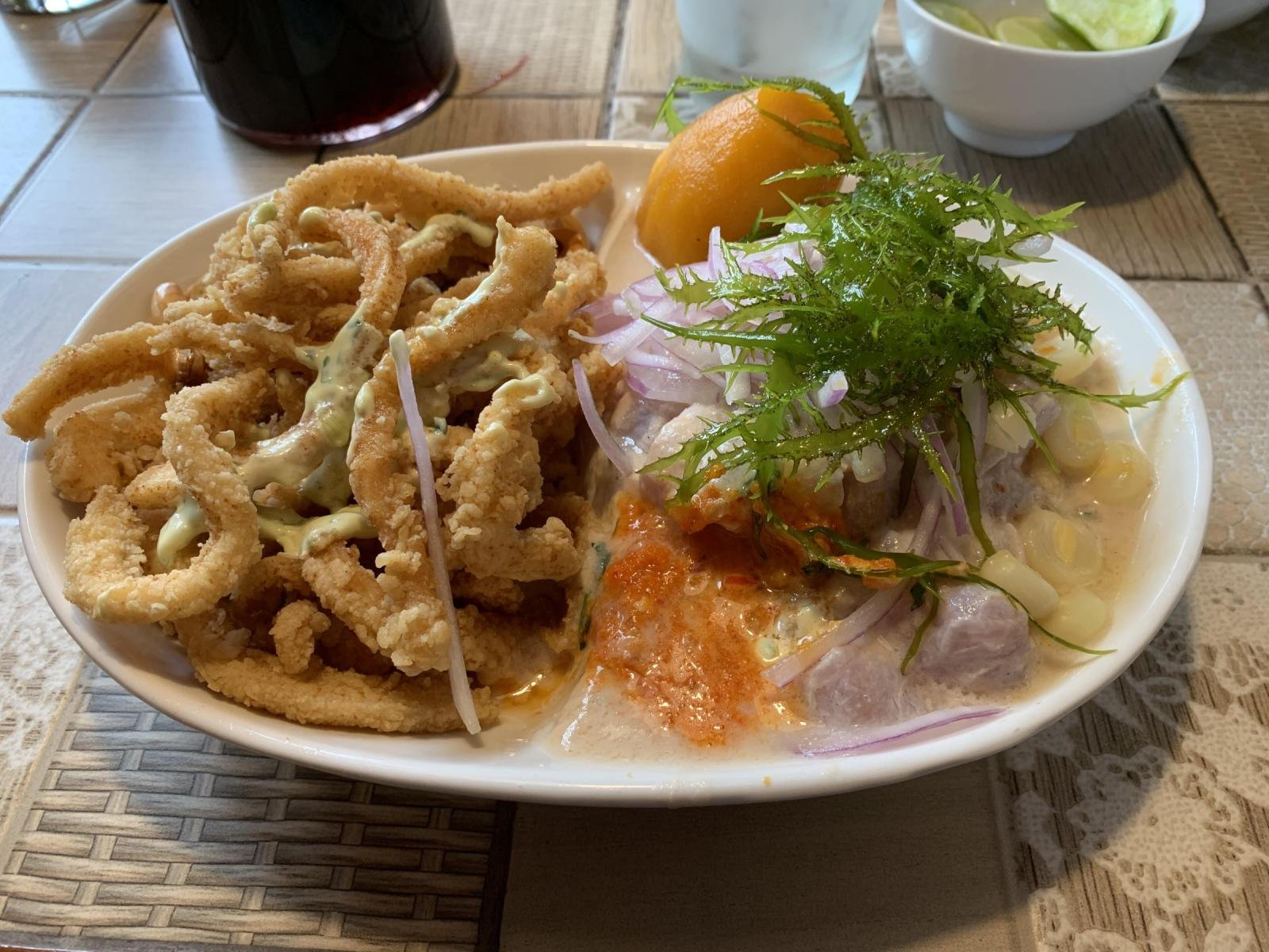 A plate of Peruvian ceviche with red onion, sweet potato, corn and fried calamari