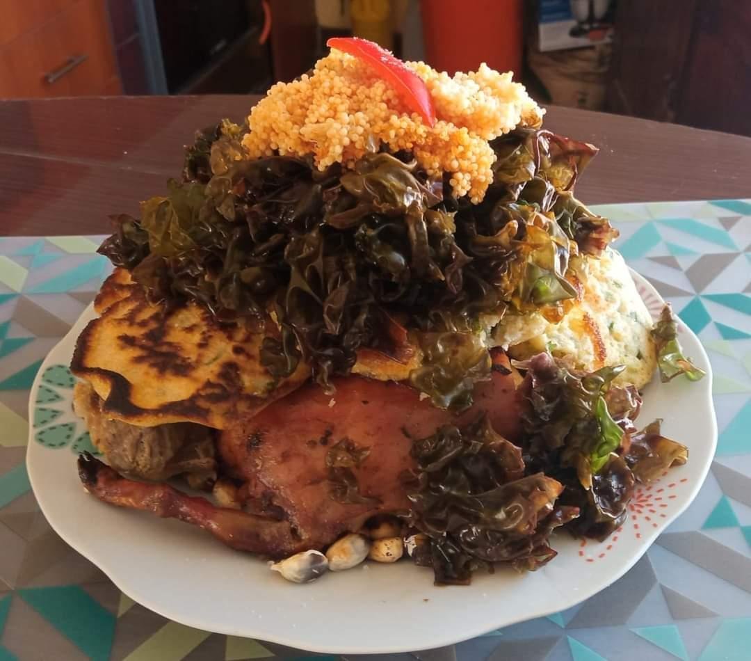 A plate of chiriuchu from Cusco with roast cuy, a corn tortilla, seaweed, toasted corn and red rocoto on top