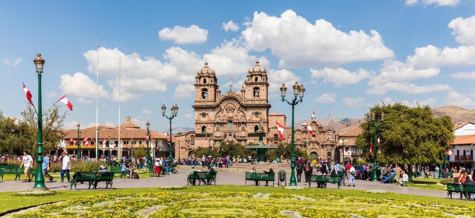 Plaza de Armas of Cusco with the church of La Compania and flower beds under a blue sky