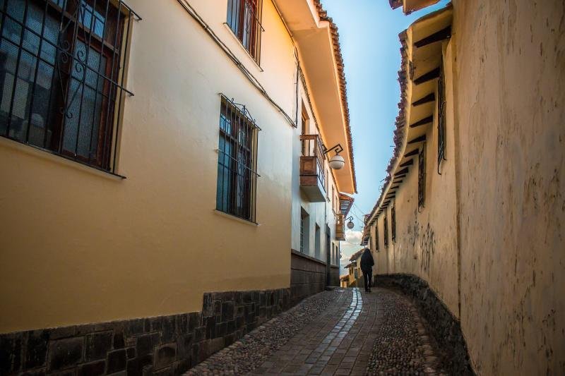 Narrow cobbled lane with white walls and balconies in the San Blas neighborhood of Cusco