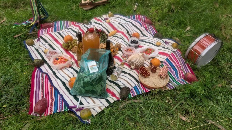 Despacho offering laid out on a striped cloth with coca leaves, grains, fruit and sweets