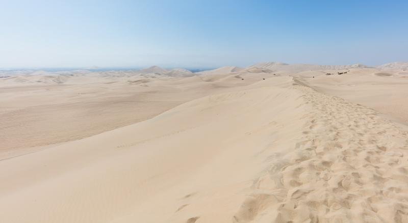 Rolling sand dunes near Ica under a pale blue sky