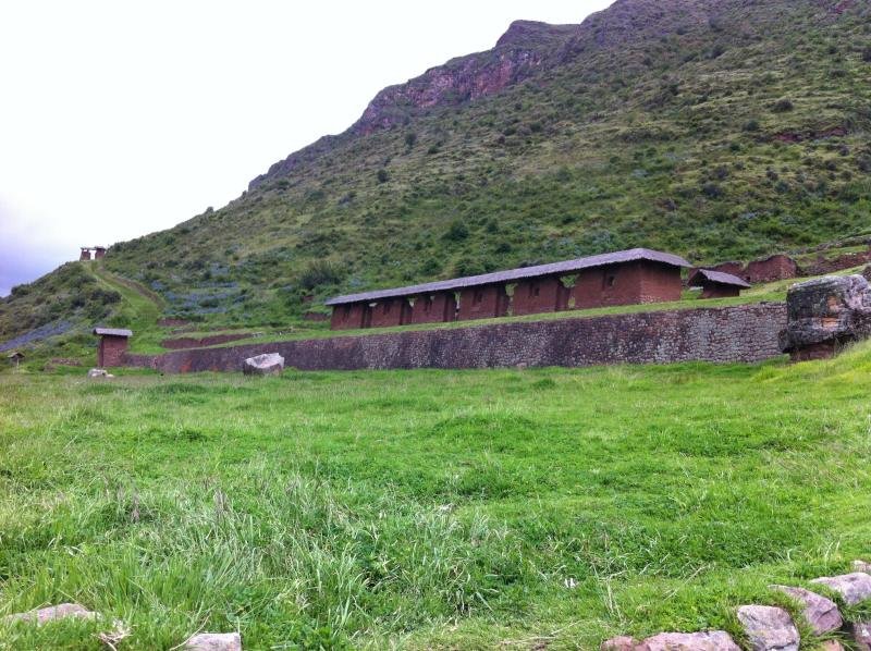 The long kallanka hall of Huchuy Qosqo beside a grassy esplanade