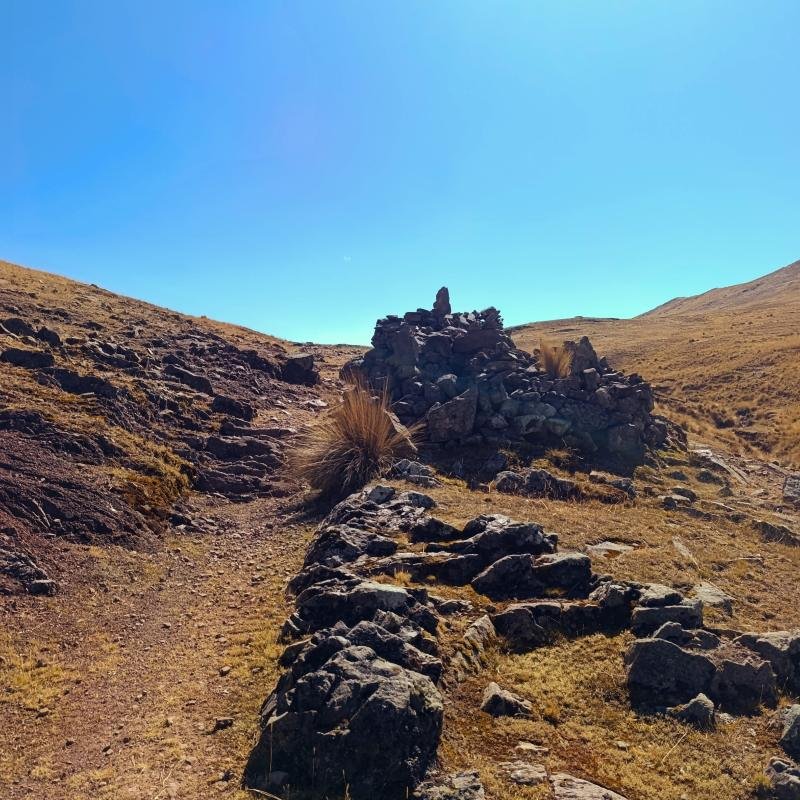 Stone cairn beside the trail across the grassland toward Huchuy Qosqo