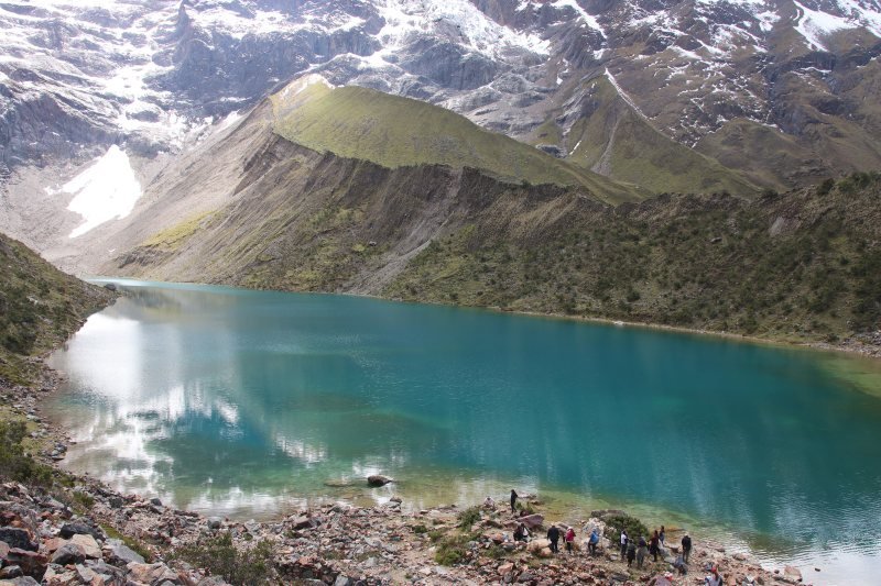 Visitors on the shore of turquoise Humantay Lake below the glacier