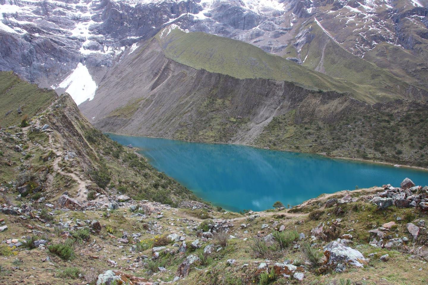 Trail along the ridge above Humantay Lake with snow peaks behind