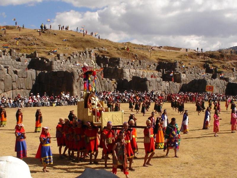 Inti Raymi performers carrying the Inca on a golden litter across the esplanade of Sacsayhuaman