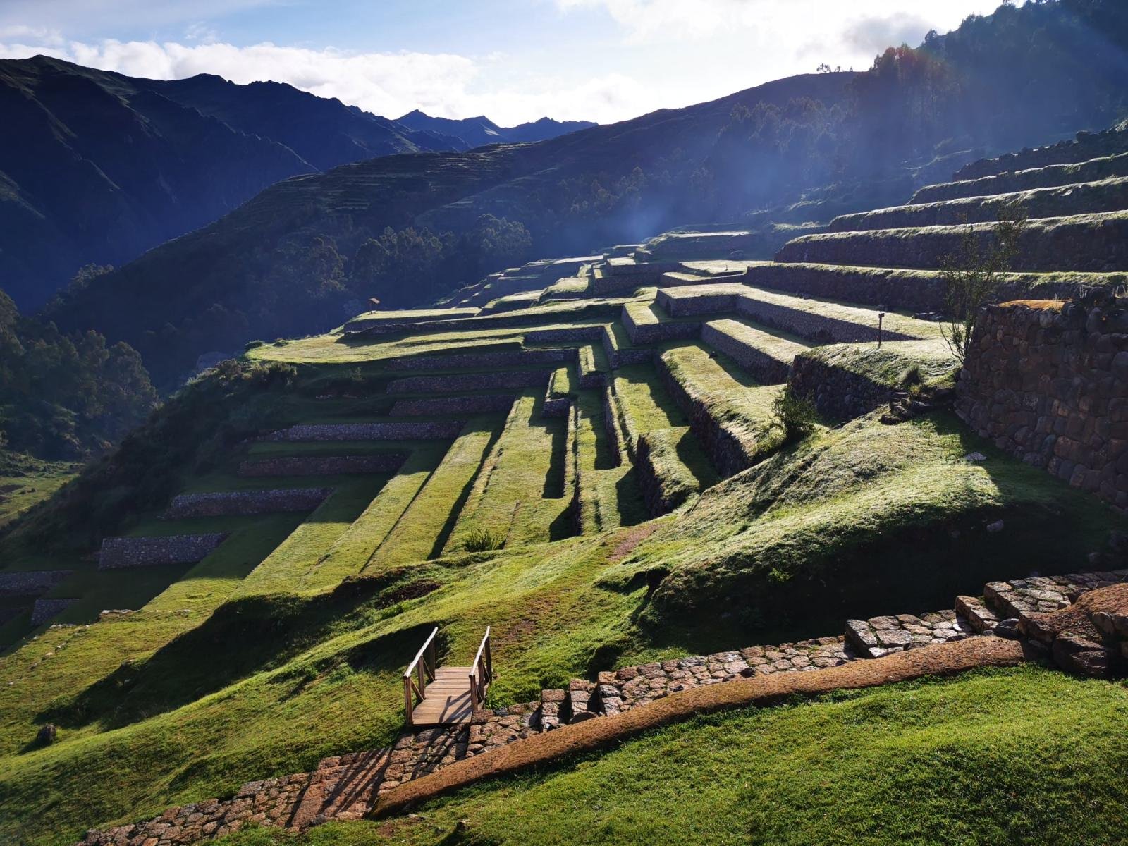Green Inca terraces of Chinchero in the January sun with Sacred Valley mountains behind
