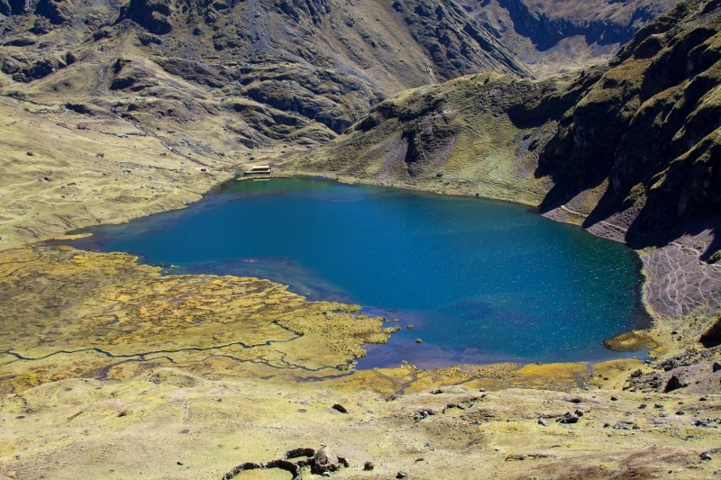 Blue alpine lake in a grassy basin on the Lares trek
