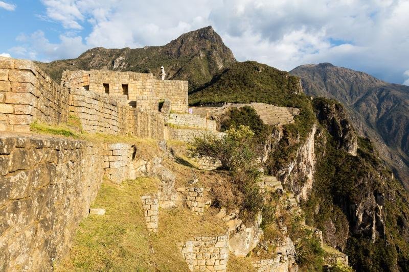 Stone buildings of Machu Picchu on the edge of the cliff with mountains behind