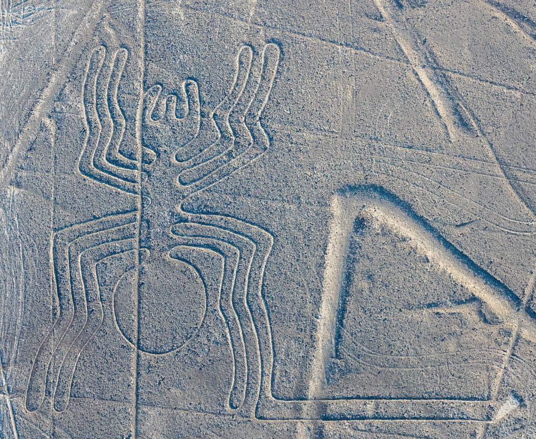 The spider figure of the Nazca Lines seen from the air, with straight lines cros The spider figure of the Nazca Lines seen from the air, with straight lines crossing the desert
