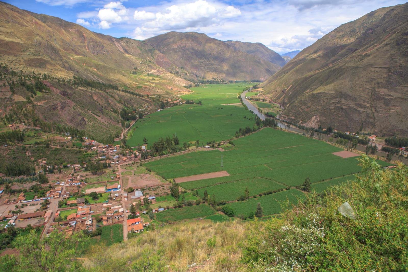 Green fields of the Sacred Valley, the Vilcanota River and a town seen from above