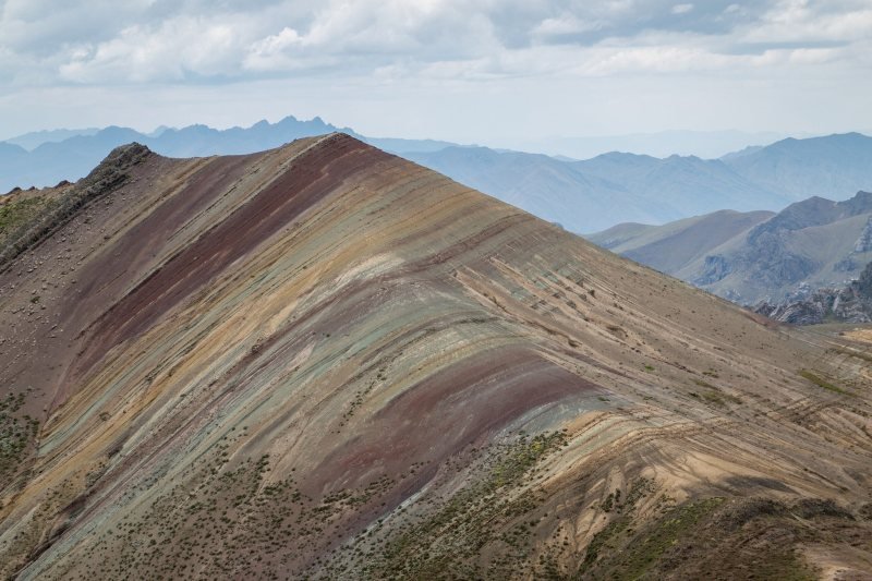 Banded mountain slope at Palccoyo with layered peaks in the distance