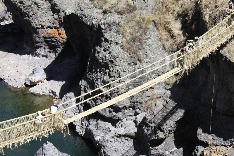 Visitors crossing the woven grass rope bridge of Qeswachaka over the Apurimac gorge