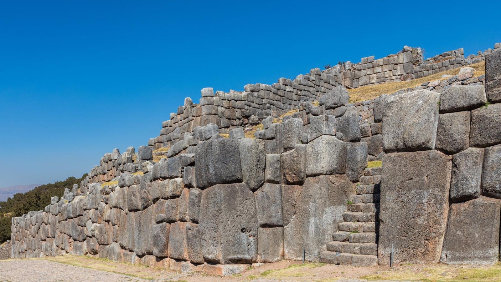 Zigzag Inca walls of Sacsayhuamán built from huge fitted stones under a deep blue sky