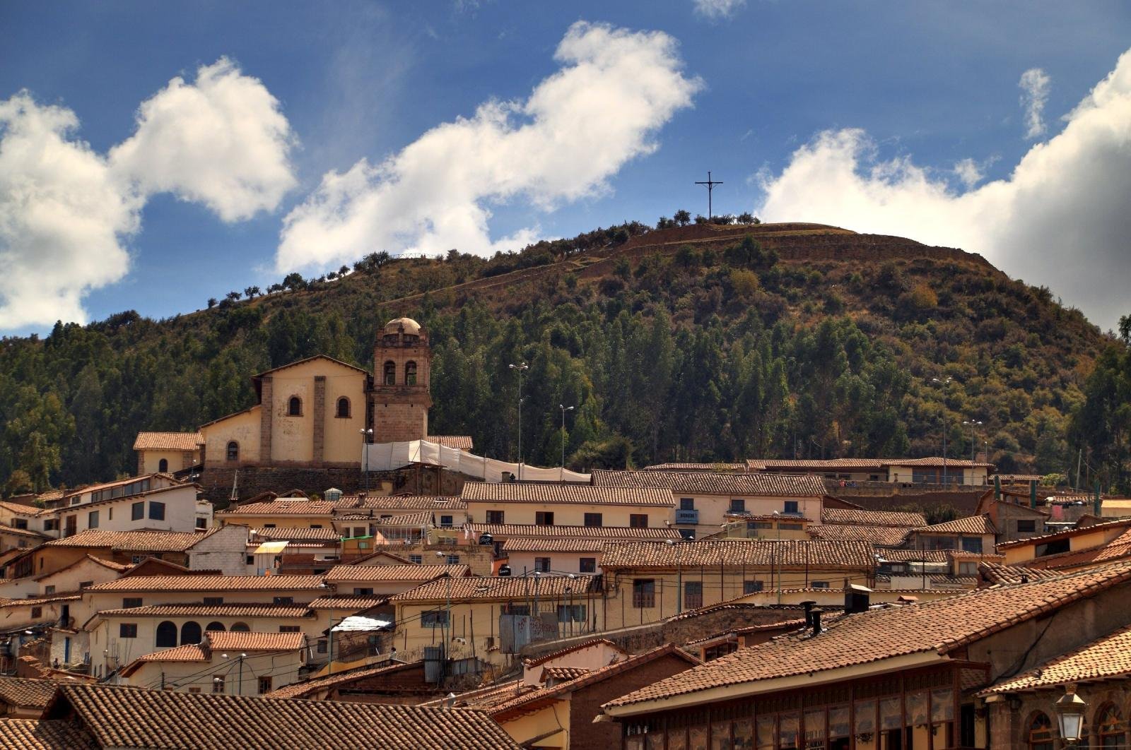 San Cristobal church above the tiled roofs of Cusco, with the hill of Sacsayhuaman behind