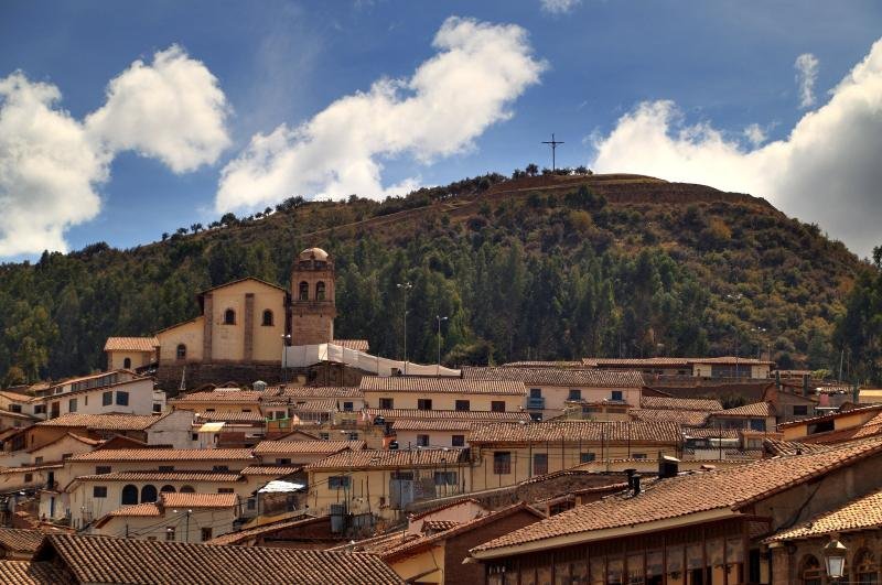 San Cristobal church above the tiled roofs of Cusco, with the hill of Sacsayhuaman behind