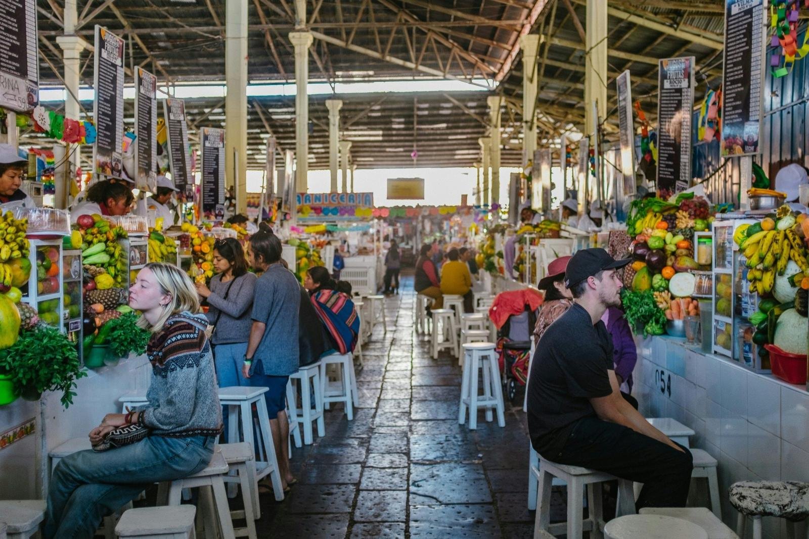 Fruit juice stalls and shoppers inside San Pedro market in Cusco