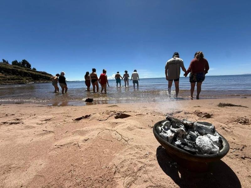 Ceremony on Lake Titicaca Travelers wading into Lake Titicaca during an offering ceremony, with a smoking brazier on the beach