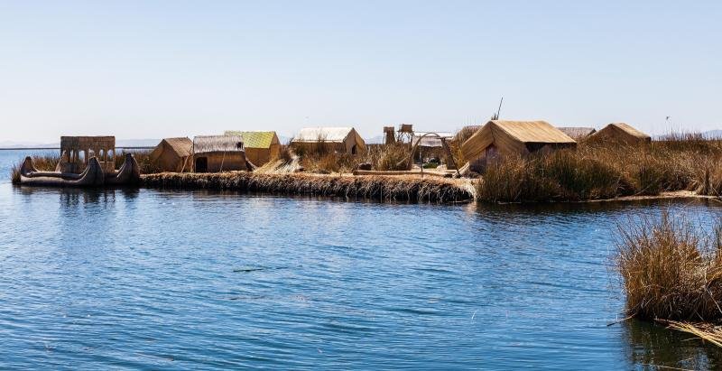 Floating Uros island with reed huts at the water's edge on Lake Titicaca