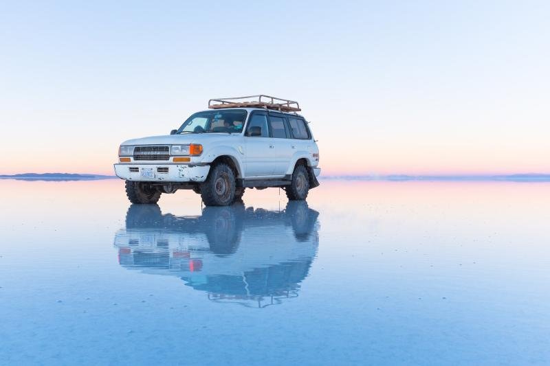 Salar de Uyuni mirror Four-wheel-drive vehicle reflected on the flooded Salar de Uyuni