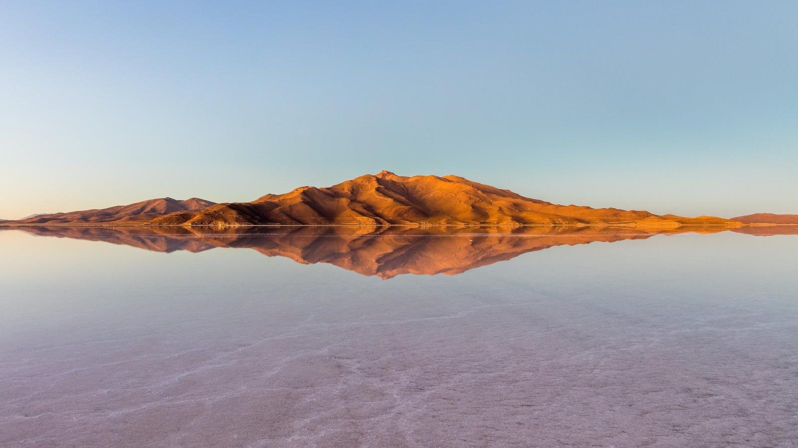 Mountain reflected in the flooded Salar de Uyuni at dusk