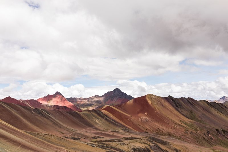 Red and ochre ridges of the Vinicunca range under a cloudy sky
